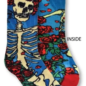 K&ouml;nnte beinhalten: Ein Paar bunte Socken mit einem Skelett- und Rosenmuster. Die Socken sind blau, rot, gr&uuml;n und gelb. Die W&ouml;rter "AUSSEN" und "INNEN" sind auf den Socken aufgedruckt.