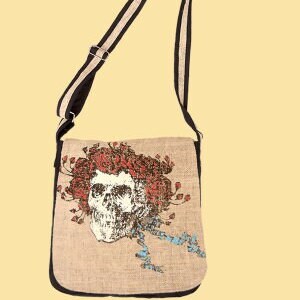 May include: A brown canvas shoulder bag with a black and white striped strap. The bag features a printed image of a skull with red roses and blue ribbon.
