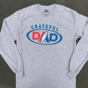May include: Gray long-sleeve t-shirt with a blue and red oval graphic that says "GRATEFUL DAD" with a lightning bolt design inside the oval.