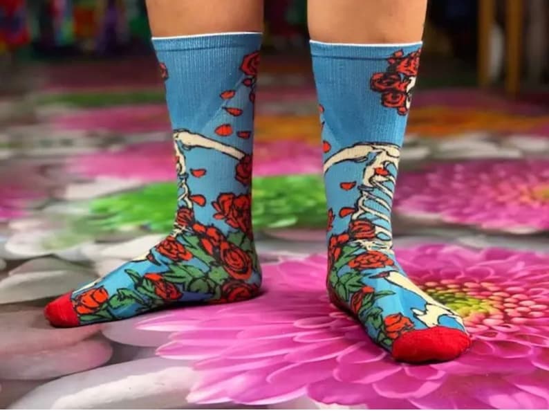 K&ouml;nnte beinhalten: Ein Paar blaue Socken mit einem roten, wei&szlig;en und gr&uuml;nen Blumenmuster. Die Socken haben ein Skelett-Design und sind aus einem weichen, bequemen Material gefertigt.
