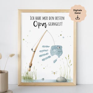 Könnte beinhalten: Gerahmter Druck mit hellem Holzrahmen. Das Kunstwerk zeigt einen Handabdruckfisch, der von einer Angelrute gefangen wird. Der Text oben lautet "Ich habe mir den besten Opa geangelt!" mit einem Symbol für den digitalen Dateidownload.