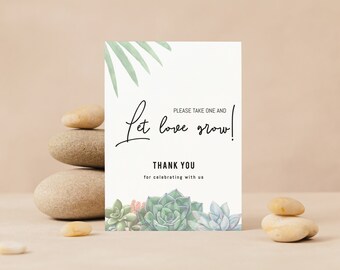 May include: White card with green foliage and succulent plants at the bottom. The text reads "Let love grow!" with "Please take one and" above it. Below the image is the text "Thank you for celebrating with us."