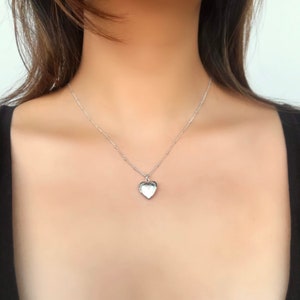 May include: A silver heart-shaped locket necklace on a delicate chain.