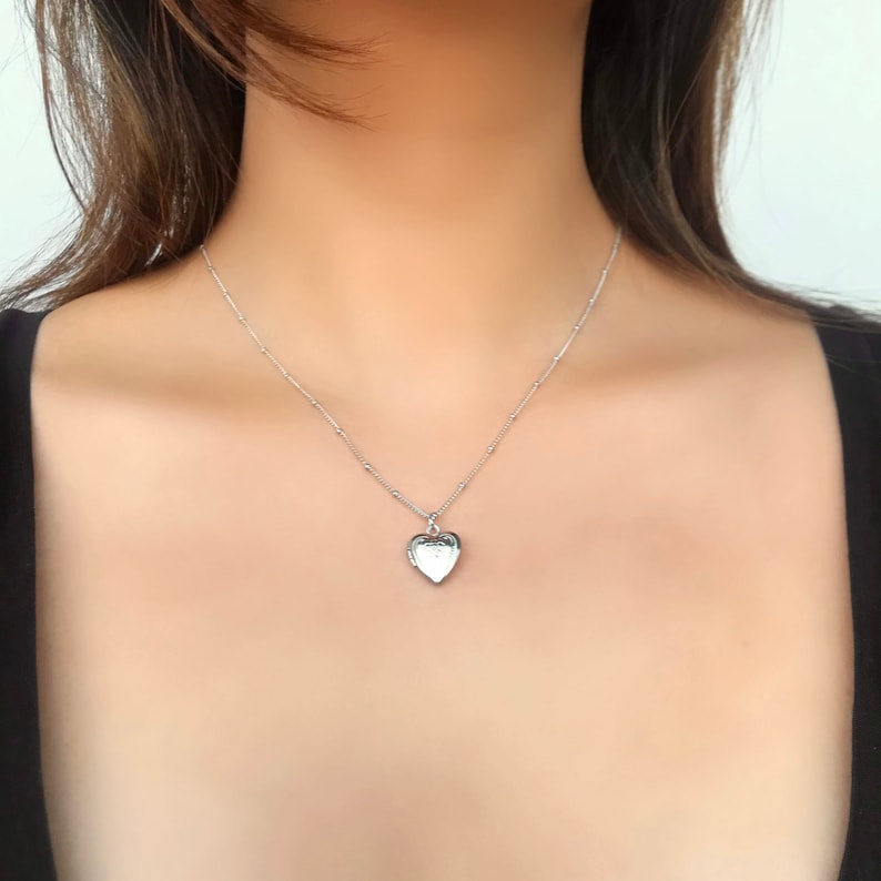 May include: A silver heart-shaped locket necklace on a delicate chain.