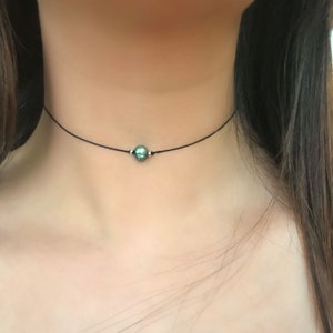 May include: A simple black choker necklace with a single green gemstone pendant.