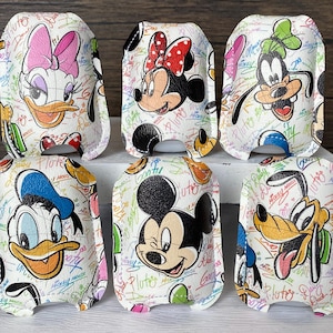 May include: Six white leather cases featuring Disney characters Daisy Duck, Minnie Mouse, Goofy, Donald Duck, Mickey Mouse, and Pluto. Each case has a colorful graffiti-style background with character names and phrases.