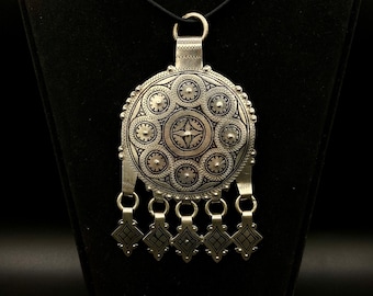 May include: A silver pendant necklace with a round, ornate design and a fringe of small, diamond-shaped charms.