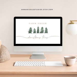 Pode incluir: Um monitor de computador exibe uma impressão de arte digital com o texto "FARM FRESH christmas trees". O design apresenta árvores de Natal verdes brilhantes. O monitor está em uma mesa de madeira clara com uma lâmpada dourada e uma xícara de café.