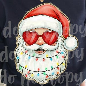 May include: A navy blue sweatshirt featuring a Santa Claus graphic. Santa is wearing heart-shaped sunglasses and a red hat. His beard is adorned with colorful Christmas lights, creating a festive holiday design.