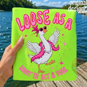 May include: A neon green t-shirt with the phrase "LOOSE AS A ABOUT TO ACT A FOOL" in pink, featuring a cartoon goose wearing sunglasses, a pink boa, and a pearl necklace. The design includes pink stars and the words "original designer" and "Electric Edge Designs".