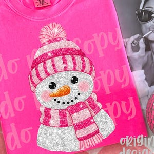 May include: A vibrant pink Comfort Colors sweatshirt with a glittery snowman design. The snowman has a pink and white striped hat and scarf, a carrot nose, and black eyes. The text "do copy" is printed on the shirt.