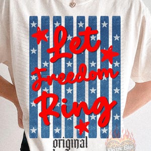 May include: Cream-colored t-shirt with a patriotic design. The graphic features the words "Let Freedom Ring" in red script over a blue and white striped background with stars. The words "original designer" are printed below.