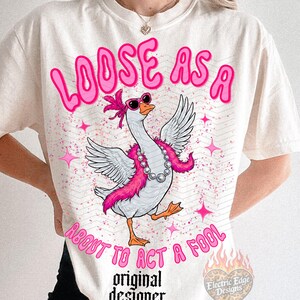 May include: Off-white t-shirt featuring a goose graphic with sunglasses and a pink boa. The text "LOOSE AS A ABOUT TO ACT A FOOL" is above the goose. The words "original designer" are below the goose.