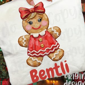 May include: White pillow with a gingerbread girl design. The gingerbread girl has a red dress, bow, and rosy cheeks. The text "Bentli" is in red at the bottom. The words "original designer" are also visible.