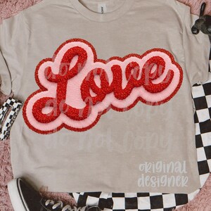 May include: A light tan t-shirt with the word "Love" in a red, textured font with a pink outline. The shirt is paired with black and white checkered pants and black sneakers.