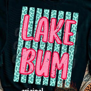 May include: Black sweatshirt with the words "LAKE BUM" in pink, set against a teal leopard print background. The design includes vertical stripes and the words "original designer" at the bottom. Leopard print shoes are visible.