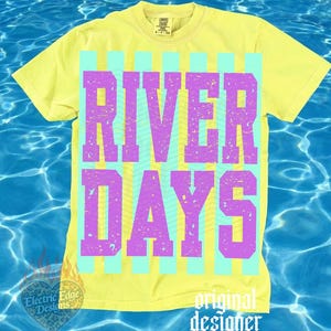 May include: A yellow t-shirt with the words "RIVER DAYS" in purple block letters, set against a background of vertical light blue stripes. The shirt has a vintage, distressed look, with the words slightly faded. The words "original designer" are at the bottom.