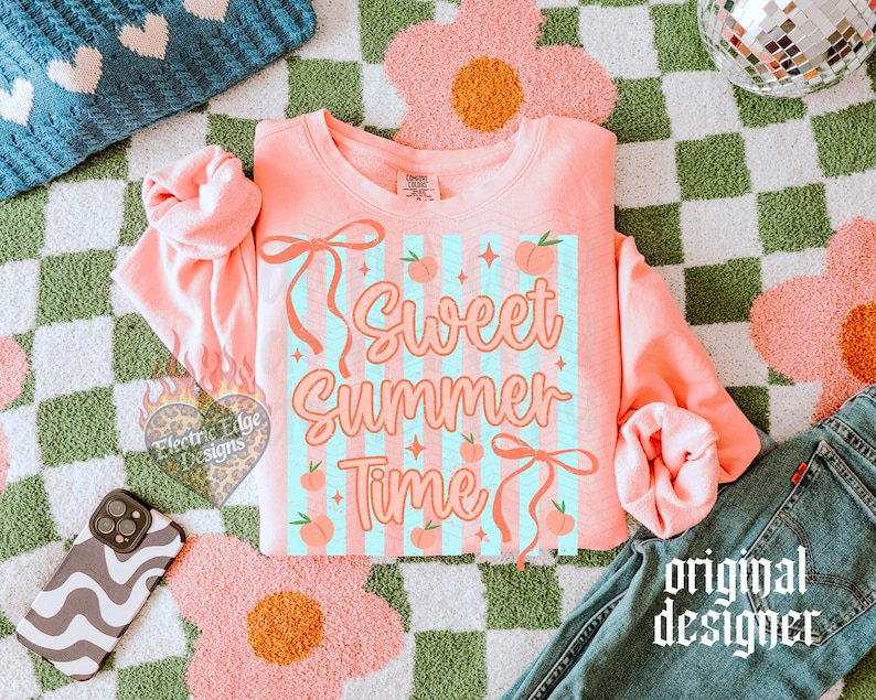 May include: A coral-colored sweatshirt with the text "Sweet Summer Time" in a retro font, featuring peaches and bows. The design is set against a light blue striped background. The sweatshirt is paired with blue jeans and a patterned phone case.