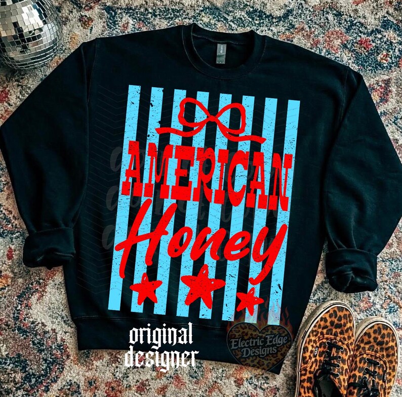 May include: Black sweatshirt with the words "AMERICAN Honey" in red, set against a backdrop of light blue vertical stripes. The design includes a red bow and three red stars. The words "original designer" are at the bottom.
