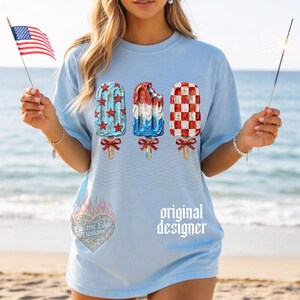 Pu&ograve; includere: T-shirt azzurra con tre disegni di ghiaccioli rossi, bianchi e blu, a tema patriottico. La maglietta presenta anche la scritta "original designer" e una grafica a forma di cuore con la scritta "Electric Edge Designs".