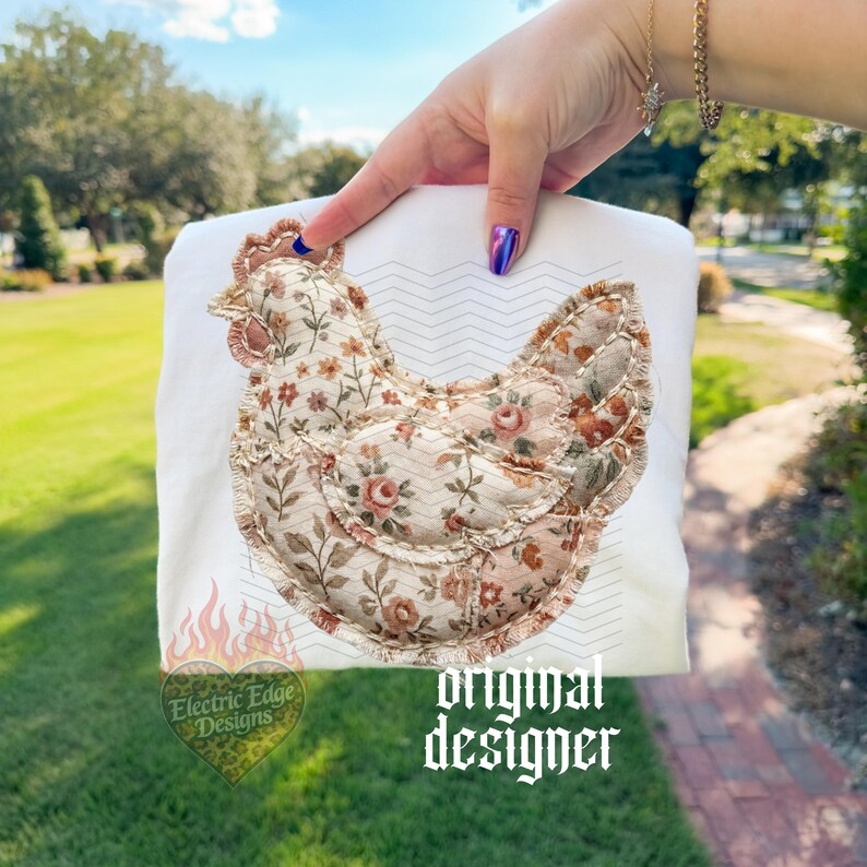 May include: White sweatshirt featuring a floral chicken design. The chicken is made of fabric with a floral pattern in shades of brown, pink, and cream. The sweatshirt has the text "original designer" and a logo with the text "Electric Edge Designs".
