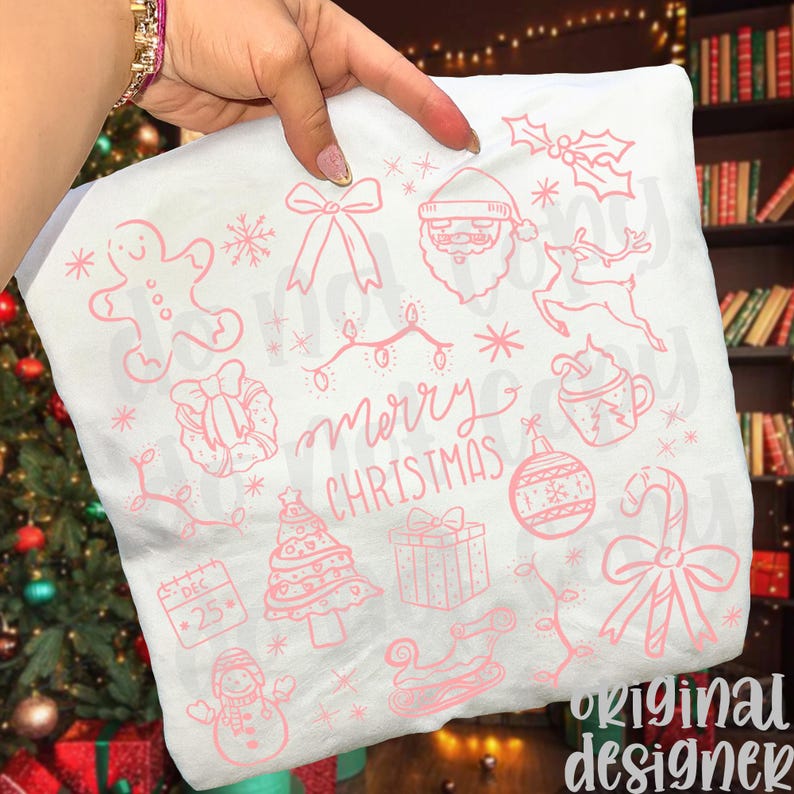 May include: White Christmas-themed pillowcase with pink illustrations. The design includes a gingerbread man, Santa Claus, reindeer, Christmas tree, ornaments, and the words "Merry Christmas". The pillowcase is held by a person.