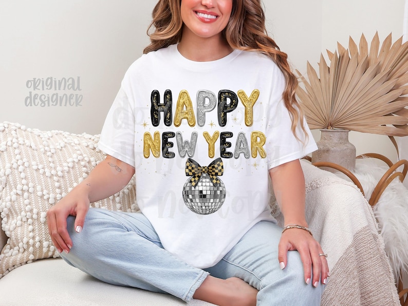 May include: White t-shirt featuring the text "HAPPY NEW YEAR" in black, gold, and silver bubble letters. A disco ball with a black and gold bow is below the text. The design is a festive choice for New Year's celebrations.