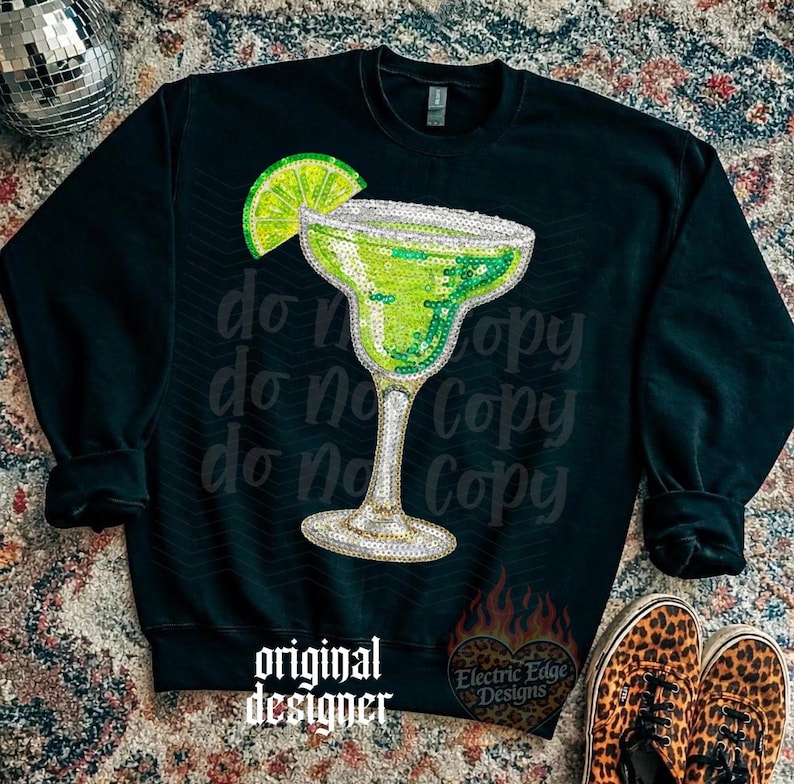 May include: Black sweatshirt featuring a sequined margarita glass with a lime wedge. The words "do not copy" are printed repeatedly on the shirt. The words "original designer" and a logo are also visible.