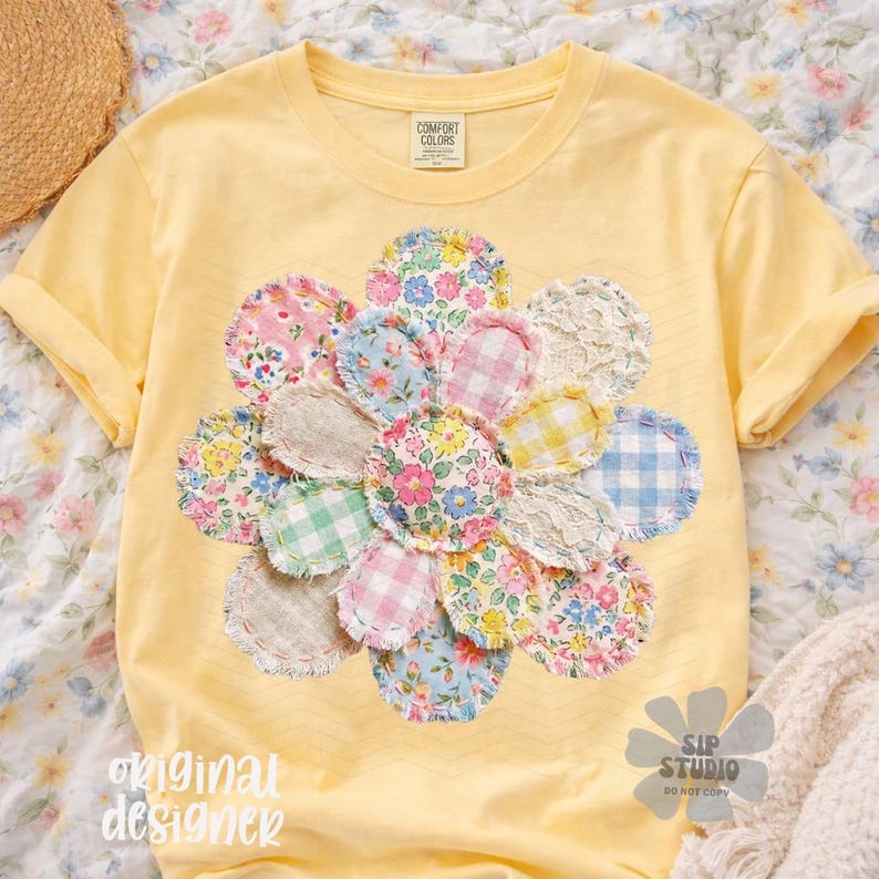 May include: Yellow t-shirt with a large floral design made of various patterned fabric circles. The flower design includes pink, blue, and yellow floral and gingham patterns. The shirt has rolled-up sleeves and the text "original designer" is visible.