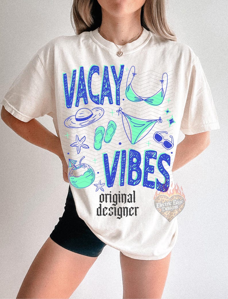Pode incluir: Camiseta creme com as palavras "VACAY VIBES" em azul, juntamente com ilustra&ccedil;&otilde;es com tema de praia em azul e verde. A camisa tamb&eacute;m apresenta o texto "original designer" em preto.