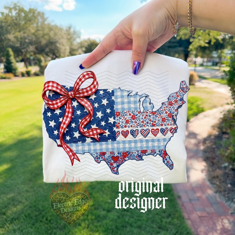 Pu&ograve; includere: T-shirt bianca con un design patriottico della mappa degli Stati Uniti. La mappa &egrave; decorata con stelle, strisce e motivi floreali rossi, bianchi e blu. Un fiocco a scacchi rosso e bianco &egrave; attaccato. Il testo "original designer" &egrave; visibile.