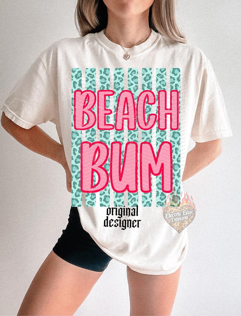 May include: Cream-colored t-shirt with the words "BEACH BUM" in pink, outlined in red, over a teal and leopard print design. The shirt also features the text "original designer" in black.