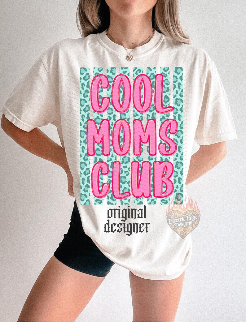 Peut inclure: T-shirt cr&egrave;me avec l'inscription "COOL MOMS CLUB" en rose, soulign&eacute;e d'un rose plus fonc&eacute;. Le texte est plac&eacute; sur un fond &agrave; imprim&eacute; l&eacute;opard turquoise. En dessous, "original designer" est &eacute;crit en police gothique.