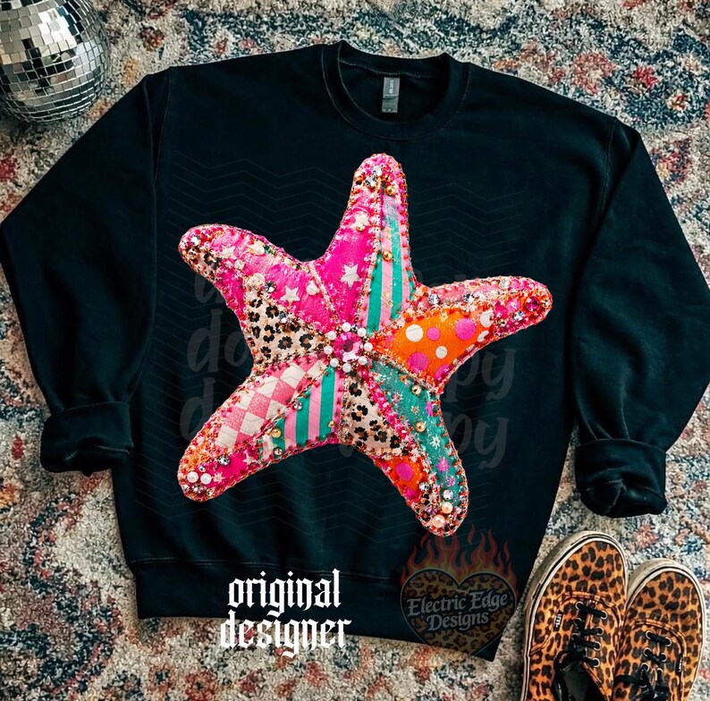 May include: Black sweatshirt featuring a large, colorful starfish design. The starfish is a patchwork of pink, orange, and teal fabrics with a leopard print accent. The words "original designer" are printed at the bottom.