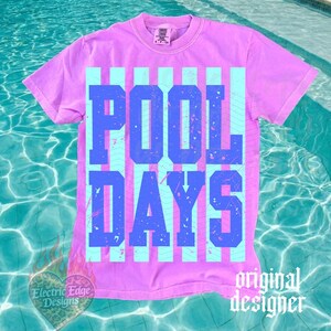 May include: A lilac t-shirt featuring the text "POOL DAYS" in blue block letters, set against light blue vertical stripes. The shirt has a crew neck and short sleeves. The words "Electric Edge Designs" and "original designer" are also visible.