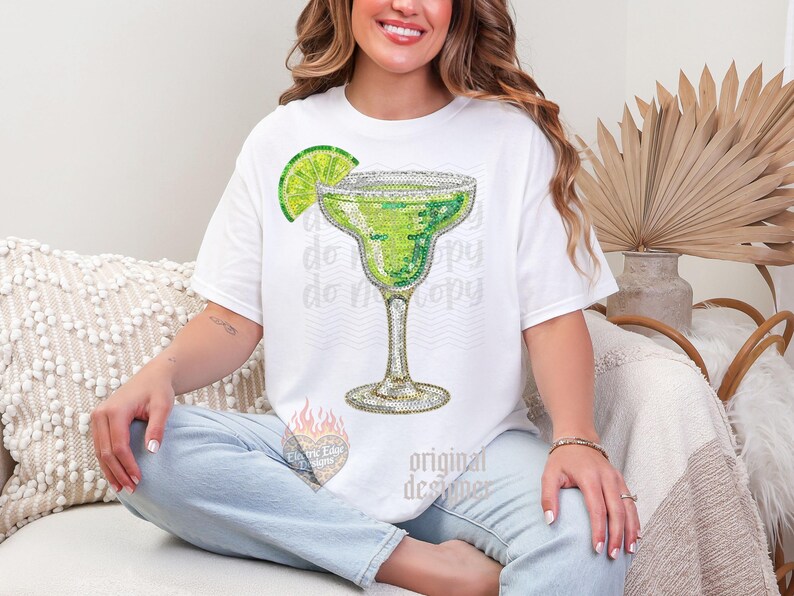 May include: White t-shirt featuring a sparkling margarita design with a lime wedge. The margarita glass is embellished with rhinestones. The words "do copy" are faintly printed on the shirt. The design is by "Original Designer".