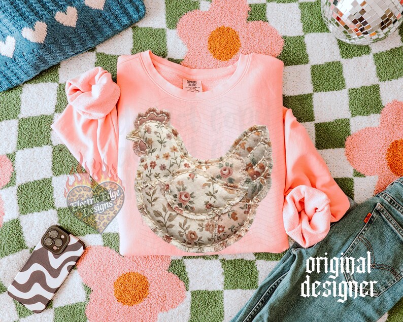 May include: A light pink sweatshirt featuring a floral chicken design. The chicken is made of a floral fabric with a quilted appearance. The words "original designer" are printed in a gothic font on the bottom right of the image.