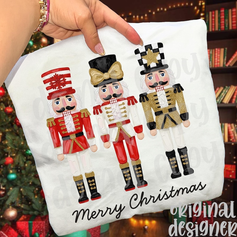 Peut inclure: Coussin blanc orn&eacute; de trois casse-noisettes color&eacute;s en uniformes rouges, blancs et dor&eacute;s. L'inscription "Merry Christmas" est imprim&eacute;e en &eacute;criture cursive. Un design festif sur le th&egrave;me de No&euml;l.
