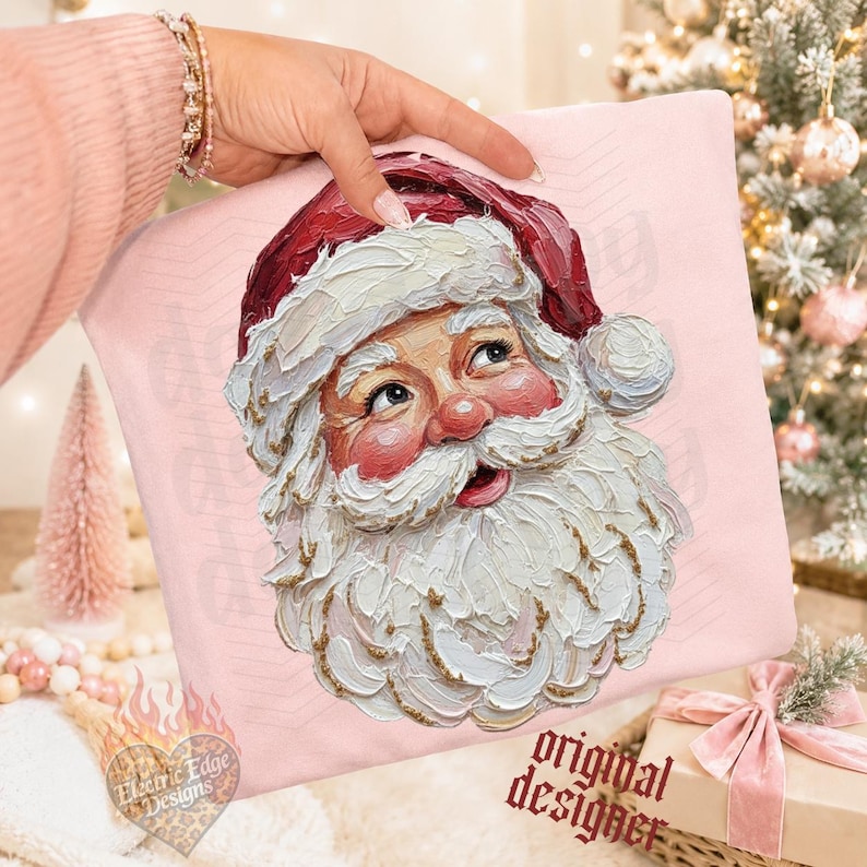 Puede incluir: Una sudadera rosa claro con un gr&aacute;fico de estilo pintura al &oacute;leo con textura impasto que representa a Santa Claus. La ilustraci&oacute;n muestra un gorro rojo oscuro, una barba blanca espesa con detalles dorados y mejillas sonrosadas, con pinceladas visibles.