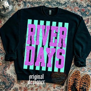 May include: Black sweatshirt with the words "RIVER DAYS" in distressed purple letters over a light blue striped background. The words "original designer" are printed at the bottom. Leopard print shoes are visible.