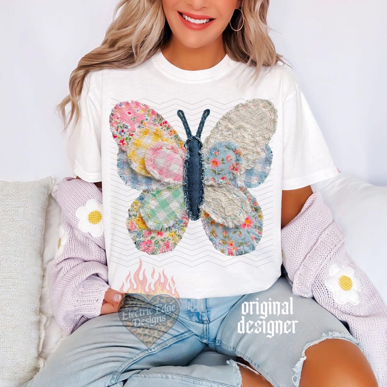 May include: White t-shirt featuring a colorful butterfly design. The butterfly is made of various patterned fabrics in pink, blue, and yellow. The shirt also has the text "Electric Edge Designs" and "original designer".