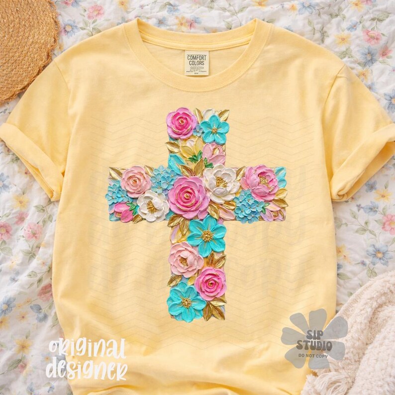 May include: Yellow t-shirt featuring a floral cross design. The cross is adorned with pink, white, and turquoise flowers. The shirt has the text "original designer" and "SIP STUDIO DO NOT COPY".