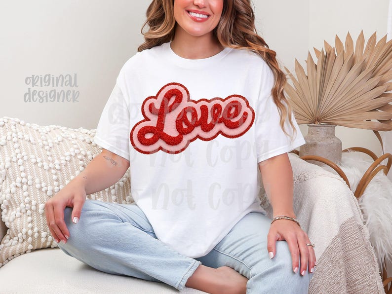 May include: White t-shirt with a red glitter "Love" design. The word "Love" is in a bold, rounded font with a pink outline. The shirt is a casual style, suitable for everyday wear.