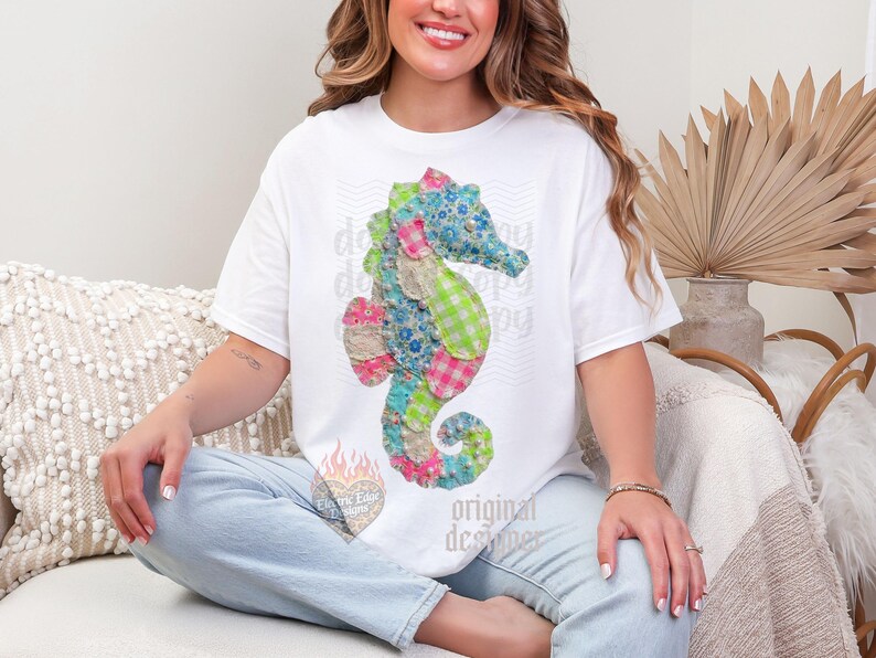 May include: White t-shirt featuring a colorful seahorse design made of patchwork fabric. The seahorse has blue floral, pink gingham, and green plaid patterns. The shirt also has the text "original designer".