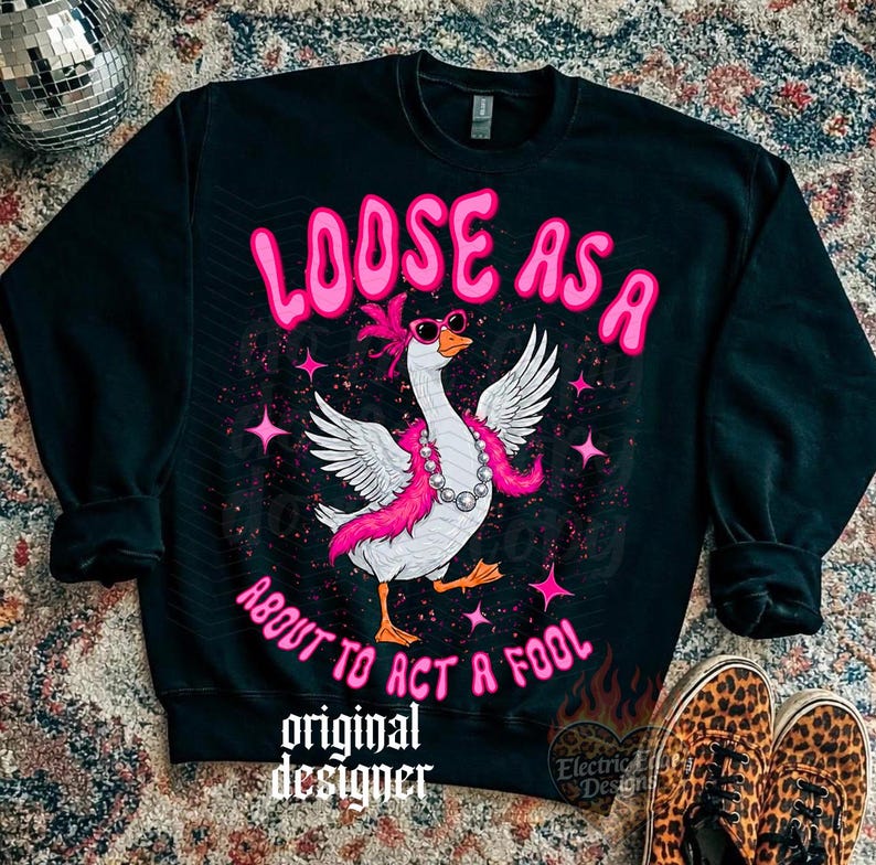 May include: Black sweatshirt featuring a goose graphic with sunglasses, a pink boa, and a pearl necklace. The text "LOOSE AS A ABOUT TO ACT A FOOL" is above and below the goose. The words "original designer" are at the bottom.