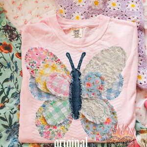 May include: A light pink Comfort Colors t-shirt featuring a patchwork butterfly design. The butterfly wings are made of various floral and patterned fabrics. The text "original designer" is printed at the bottom.