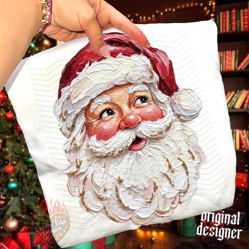 May include: A white sweatshirt featuring a textured, impasto-style painting of Santa Claus. The design displays a red hat with white trim, rosy cheeks, and a thick white beard with gold accents. The text Electric Edge Designs is visible.