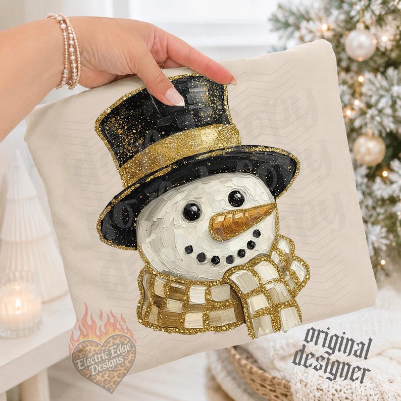 May include: A cream-colored fabric item featuring a textured, painted-style illustration of a snowman wearing a black top hat with a gold glitter band and a matching gold and white checkered scarf. The snowman has a gold carrot nose and black eyes.