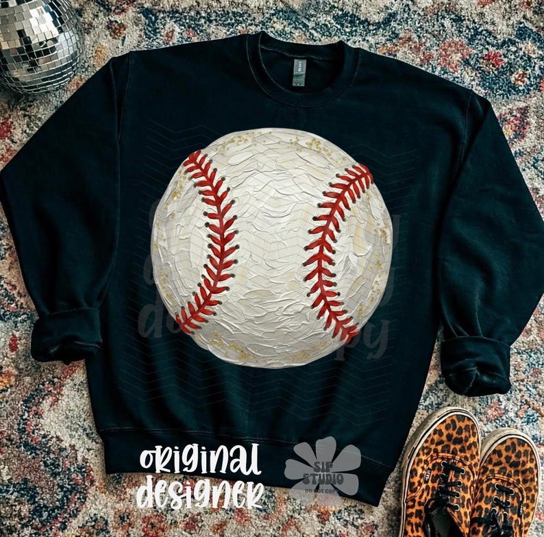 May include: A dark navy sweatshirt with a large baseball graphic. The baseball is white with red stitching. The words "original designer" are printed at the bottom. Leopard print shoes are visible.