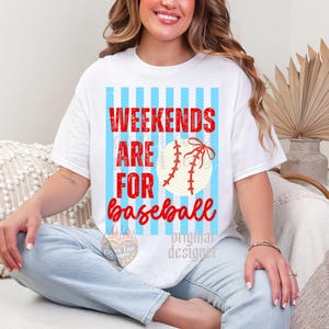 May include: White t-shirt with the text "Weekends are for baseball" in red and a baseball graphic. The design features a light blue striped background. The shirt is a casual, everyday wear item.